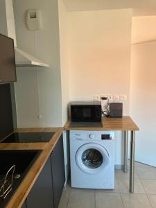 a kitchen with a washing machine and a counter at Très beau studio cosy zénith saint etienne in Saint-Étienne