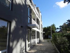 a white building with a sidewalk next to it at Alugar in Valeria del Mar