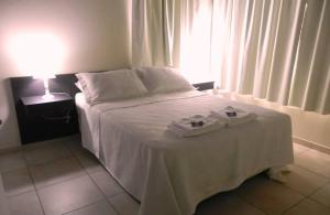 een slaapkamer met een bed met witte lakens en een raam bij Alugar in Valeria del Mar