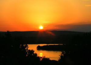 un tramonto su uno specchio d'acqua con il sole che tramonta di Apartments Biserka a Punat
