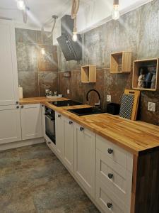 a kitchen with white cabinets and a wooden counter top at Ojcowizna na Kresach in Jurowlany