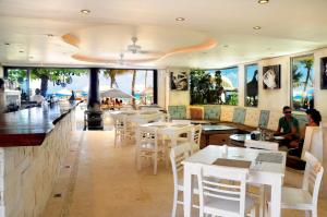 a restaurant with white tables and chairs and a bar at El Taj Oceanfront and Beachside Condo Hotel in Playa del Carmen