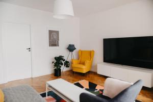 a living room with a tv and a yellow chair at Jeleni Zakątek - apartament w stolicy Karkonoszy in Jelenia Góra