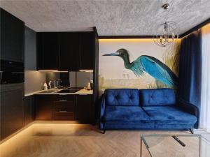 a blue couch in a kitchen with a painting of a bird at Silesia Aparthotel in Szczecin