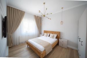 Habitación blanca con cama y lámpara de araña. en BlueSky Ultra-Central Premium Apartment, en Oradea