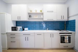 una cocina con armarios blancos y azulejos azules en BlueSky Ultra-Central Premium Apartment, en Oradea