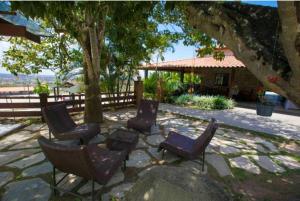 eine Gruppe von Stühlen auf einer Terrasse unter einem Baum in der Unterkunft Apart Hotel Fazenda Monte Castelo - Gravatá in Gravatá