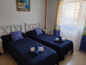 a bedroom with two beds with blue sheets and blue pillows at Cozy apartment near the ocean in Corralejo