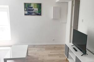 sala de estar con TV y pared blanca en Bel appartement de 40 M2 dans petite copropriété, en Le Coteau