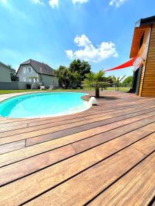une terrasse en bois à côté d'une piscine dans l'établissement Chez Seb et Lilou, à Flaxlanden