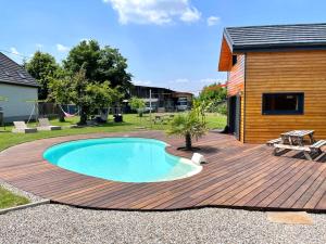 une terrasse en bois avec une piscine à l'arrière-cour dans l'établissement Chez Seb et Lilou, à Flaxlanden