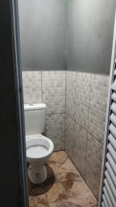 a bathroom with a toilet in a tiled room at Casas em Ubatuba in Ubatuba +4 photos