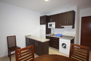 cocina con armarios marrones y lavavajillas blanco en Apartamentos Rurales Campillo, en Arroyo Frío