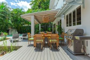 a wooden deck with a table and chairs and a grill at Peace Villa Santa Teresa - Walking distance to the beach in Santa Teresa Beach