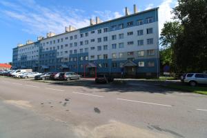 a large building with cars parked in a parking lot at Cozy apartment next to Paldiski harbor in Paldiski