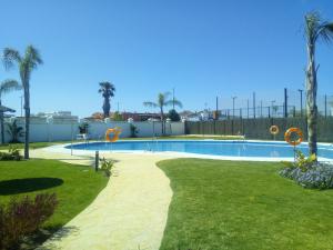 a swimming pool in a yard with palm trees at Apartamento Carlos in Rota