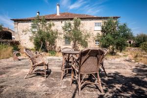 two chairs and a table in front of a building at Solar dos Carvalhos in Sernancelhe
