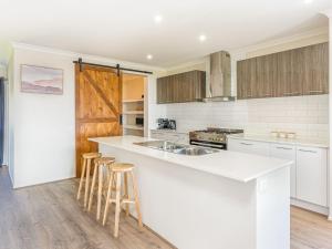 une cuisine avec un comptoir blanc et des tabourets en bois dans l'établissement 21 Peninsula View, à Cowes