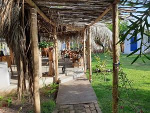 eine hölzerne Pergola mit einer Katze darunter. in der Unterkunft Pousada Casa Branca in Pôrto de Pedras + 18 Fotos
