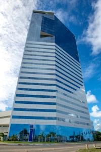 een hoog glazen gebouw met een blauwe lucht op de achtergrond bij Silverton Paiva Experience - Flat in Recife