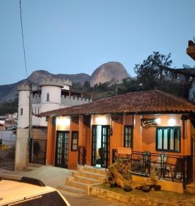 a small orange house with mountains in the background at Casa de Temporada no Centro de Pedra Azul in Pedra Azul