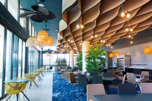 un restaurante con mesas, sillas y ventanas grandes en Rydges Gold Coast Airport en Gold Coast