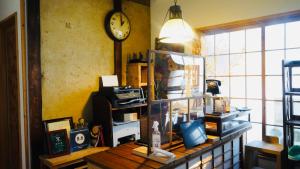 a room with a table with a clock on the wall at Guesthouse Mokumoku in Osaka