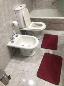 a bathroom with a toilet and a sink and red rugs at varesse house in Mar del Plata +9 photos