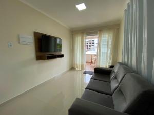 a living room with a couch and a flat screen tv at Residencial Miguel in Bombinhas