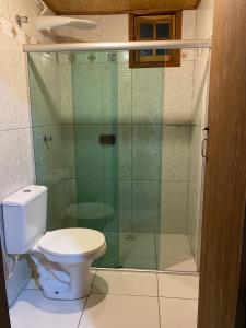 a bathroom with a toilet and a glass shower at Solar das Mangueiras - Vale do Capão in Vale do Capao