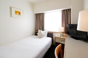 a hotel room with a bed and a television at Hotel Resol Sasebo in Sasebo