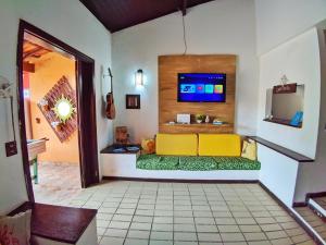 a living room with a yellow couch and a tv at Casa do Loriba com Piscina - 700 metros da praia in São Sebastião