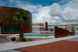 una palmera frente a un edificio con piscina en American Inn Hotel & Suites Delicias en Delicias