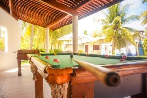 a pool table in front of a house with a pool at Bangalos do Pontal in Japaratinga