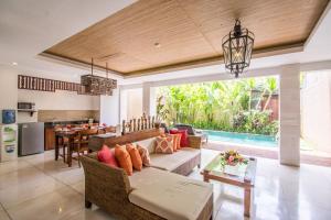 uma sala de estar com um sofá e uma mesa em Kamajaya Villas em Ubud