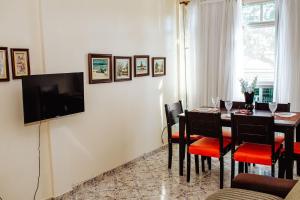 a dining room with a table and a television on a wall at Apto a 400 m da praia do Centro - WIFI 200MB - TV Smart - Cozinha equipada - Garagem - Ar condicionado in Rio das Ostras