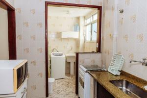 eine kleine Küche mit Spüle und Mikrowelle in der Unterkunft Ap ótima localização na praia do centro | ROFL01 in Rio das Ostras + 34 Fotos