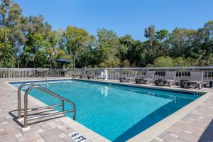 a swimming pool with chairs and an umbrella at Quality Inn Sarasota North Near Lido Key Beach in Sarasota