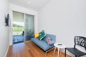 Una sala de estar con un sofá azul y una mesa. en Ocean Views 41, en Anna Bay