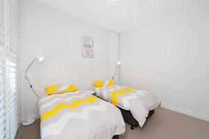 a bedroom with two beds with yellow and white pillows at Ocean Views 41 in Anna Bay