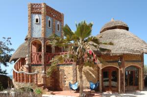 a building with a clock tower and a palm tree at Sobo Bade in Toubab Dialaw