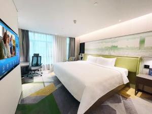 a hotel room with a large bed and a tv at Hampton by Hilton Guangzhou Tianhe Sports Center in Guangzhou