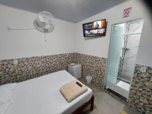 a bedroom with a bed and a shower with a fan at Pousada do Leô in Mangaratiba