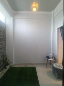a white room with a green rug and a table at Bis homestay in Sumbawa Besar