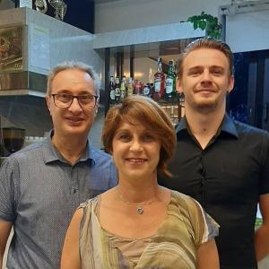 two men and a woman standing in front of a bar at Hotel Penny in Rimini