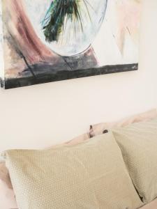 una pintura colgada sobre una cama con una almohada en Turnstone Beach House en Loorana