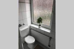 baño con aseo y ventana con planta en Trade fair and business apartment - Hannover Messe, en Hannover