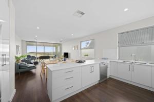 Port Noarlunga SouthMeander - Port Noarlunga South - C21 SouthCoast Holidays的带白色橱柜的厨房和客厅