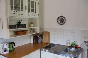 Hof Grünfelder في Friedersdorf: مطبخ مع دواليب بيضاء ومغسلة