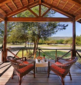 eine Veranda mit einem Tisch und Stühlen sowie Blick auf ein Feld in der Unterkunft Complejo el Paine in Villa General Belgrano